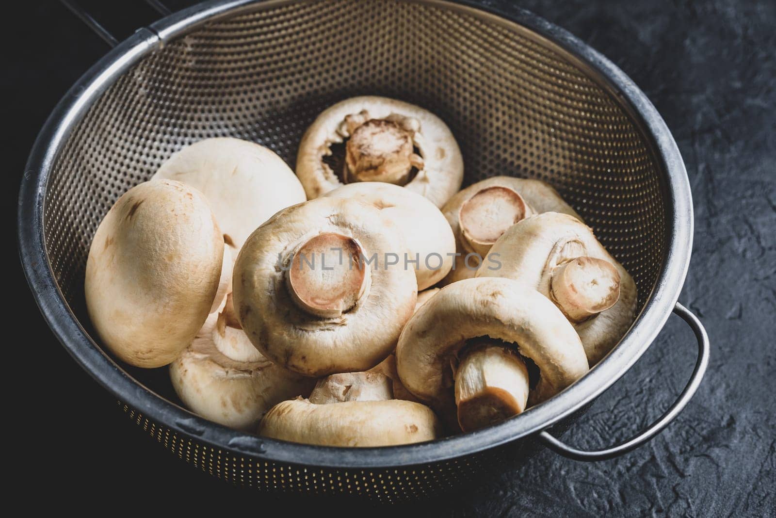 Fresh white button mushrooms in metal colander