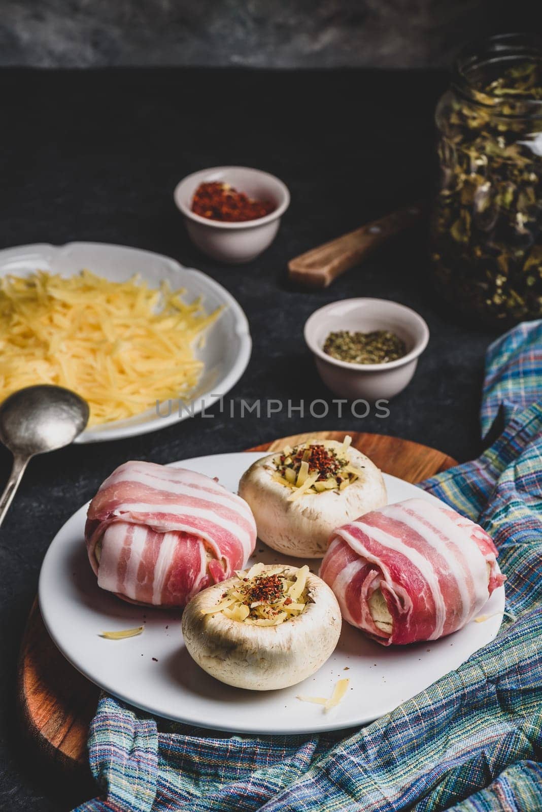 Preparing of bacon-wrapped button mushrooms stuffed with grated cheddar cheese and spices