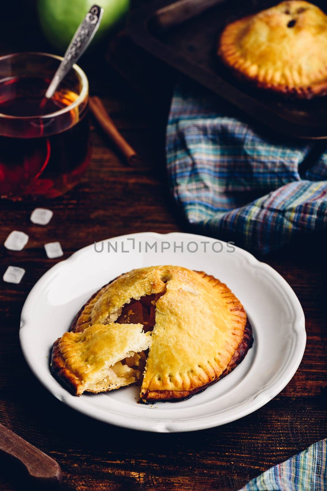 Homemade apple mini pie on white plate with cup of black tea