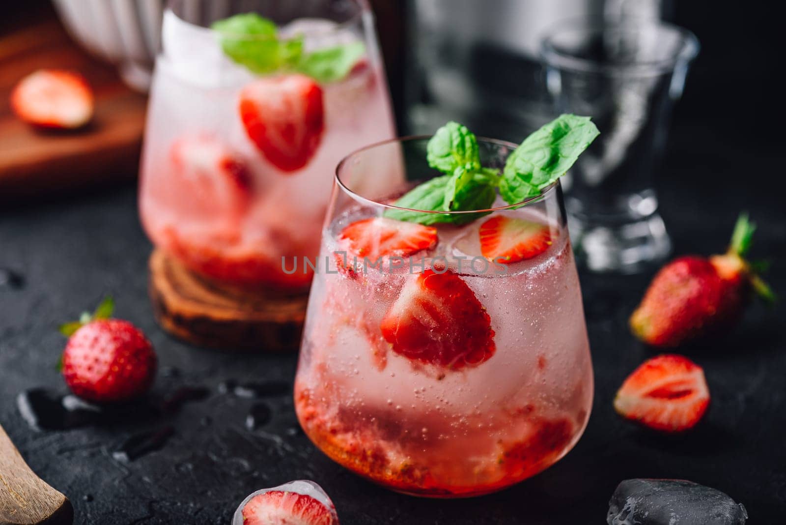 Two glasses of cocktail with fresh and frozen strawberry, gin and tonic