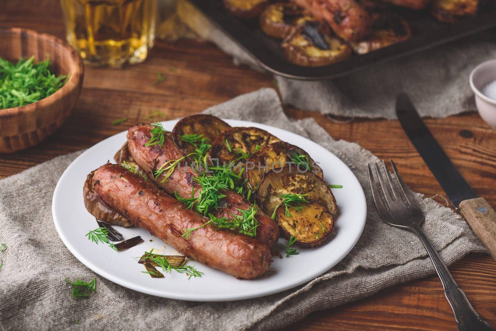 Baked Pork Sausages with Eggplant and Leek on White Plate Garnished with Fresh Herbs