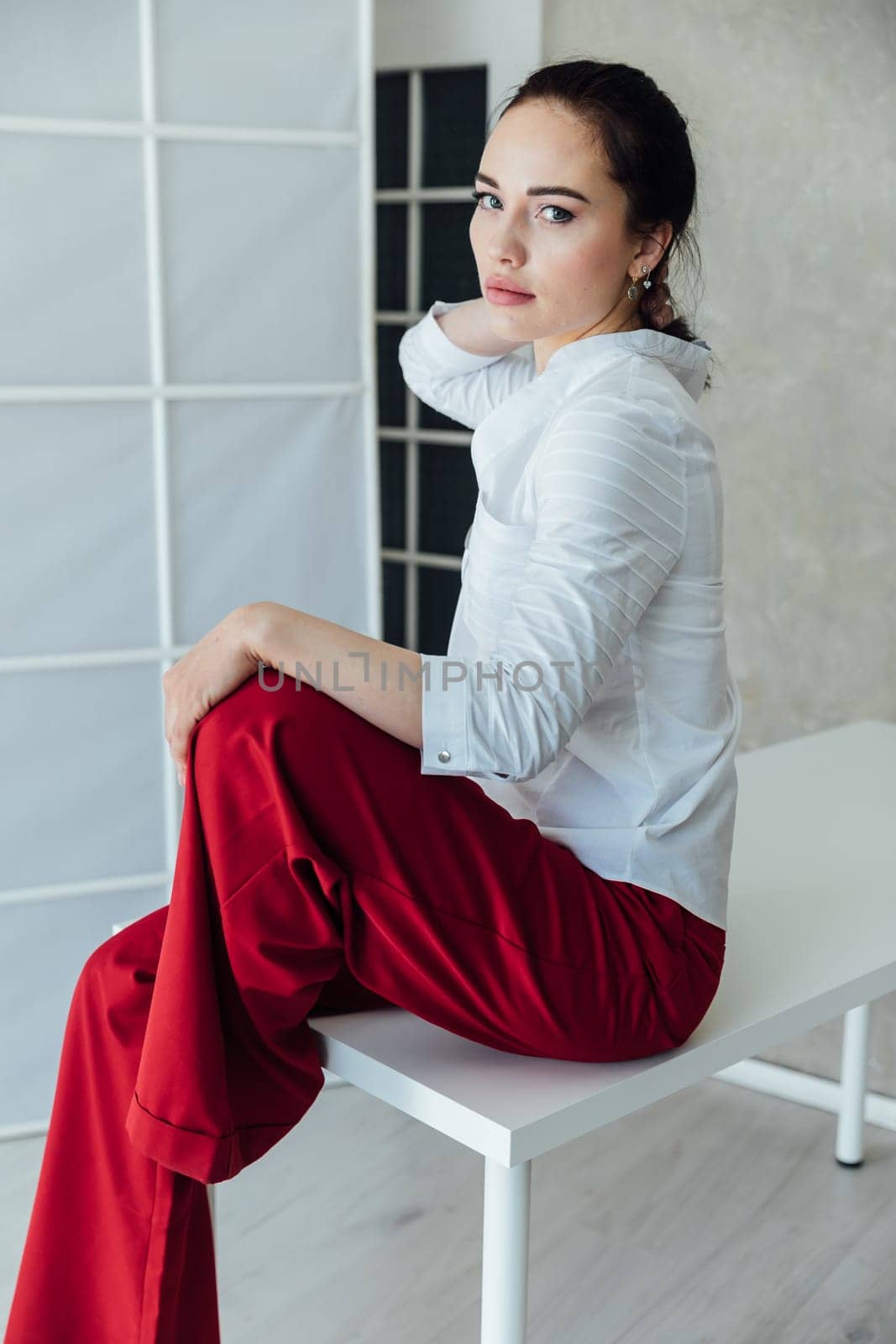 woman in red pants sits on a table in a room