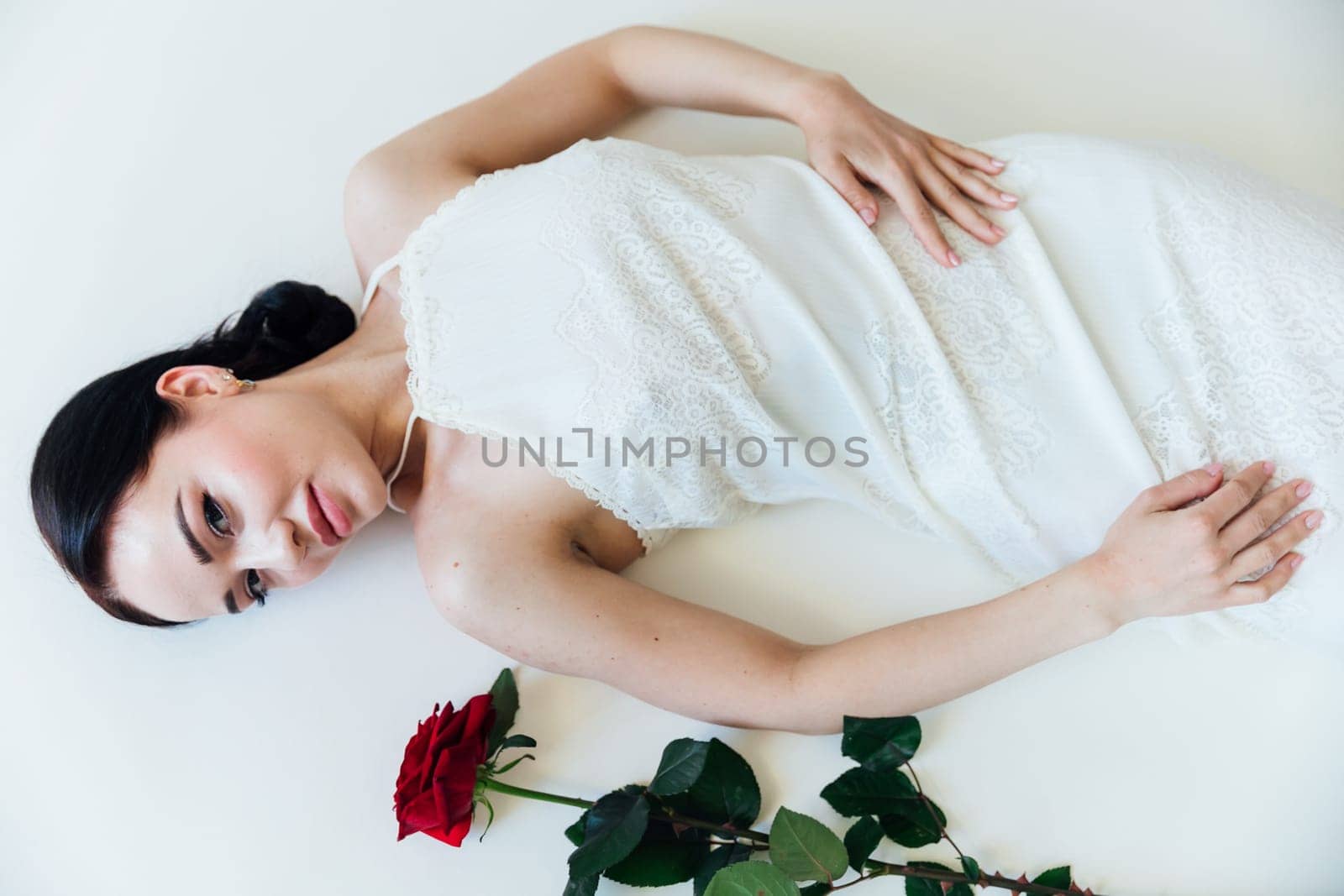 a beautiful brunette woman lies with a red rose