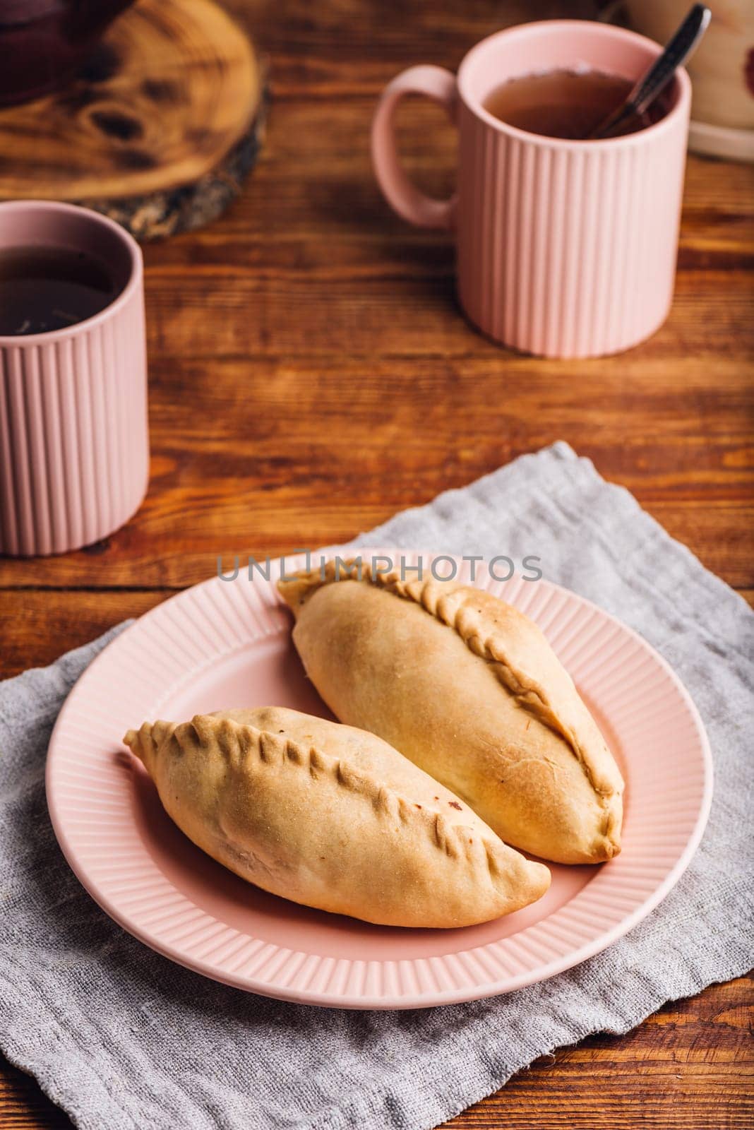 Two Homemade Cabbage Mini Pies on Plate and Mugs with Tea
