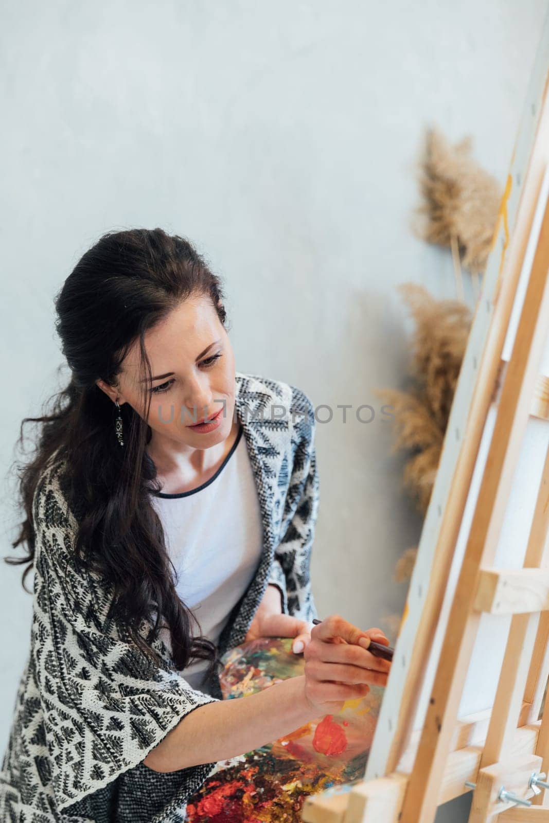 a female artist draws with a brush using a palette on an easel in an art studio teacher training