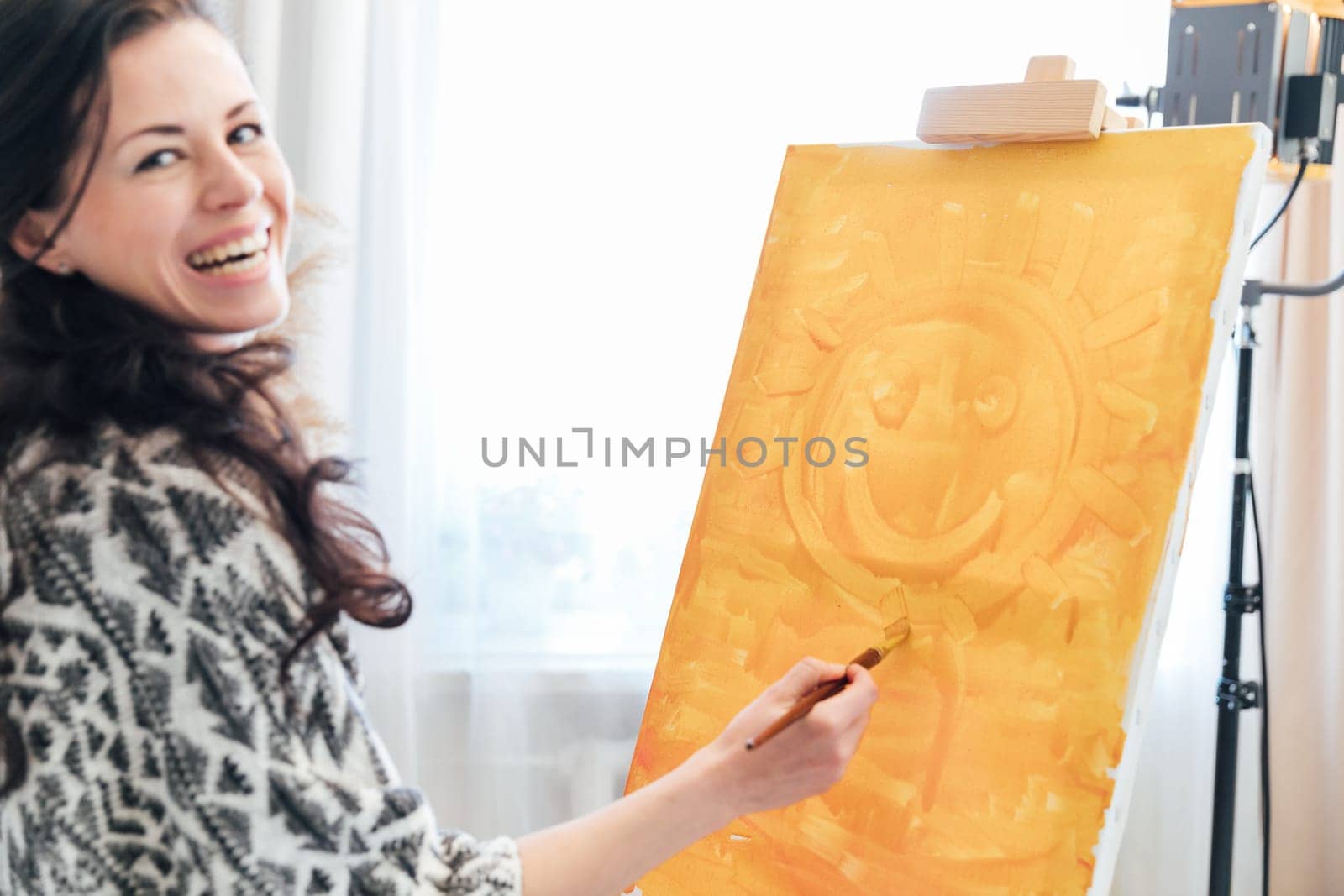 cheerful artist woman stands with a brush at the painting yellow paint