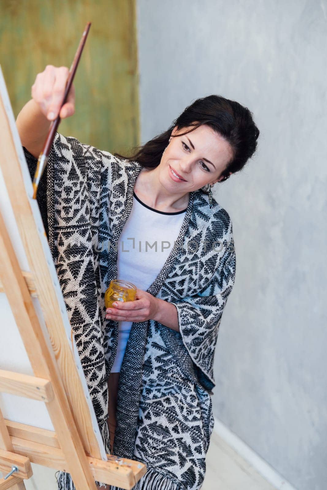 a female artist paints with a brush on an easel in an art studio