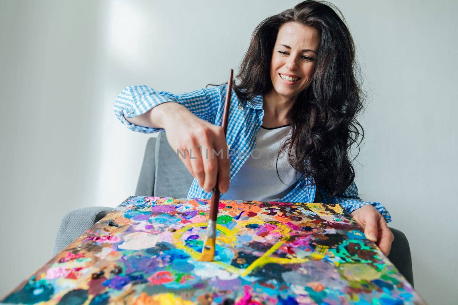a woman artist draws with brush and paints on a palette of colors