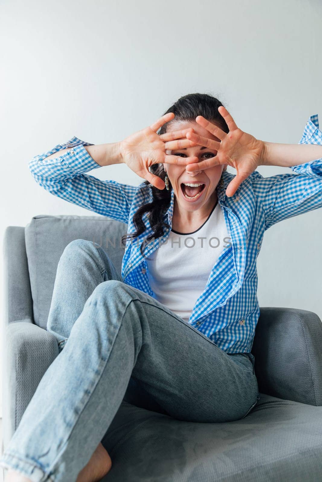 woman sits in a chair and looks through her fingers