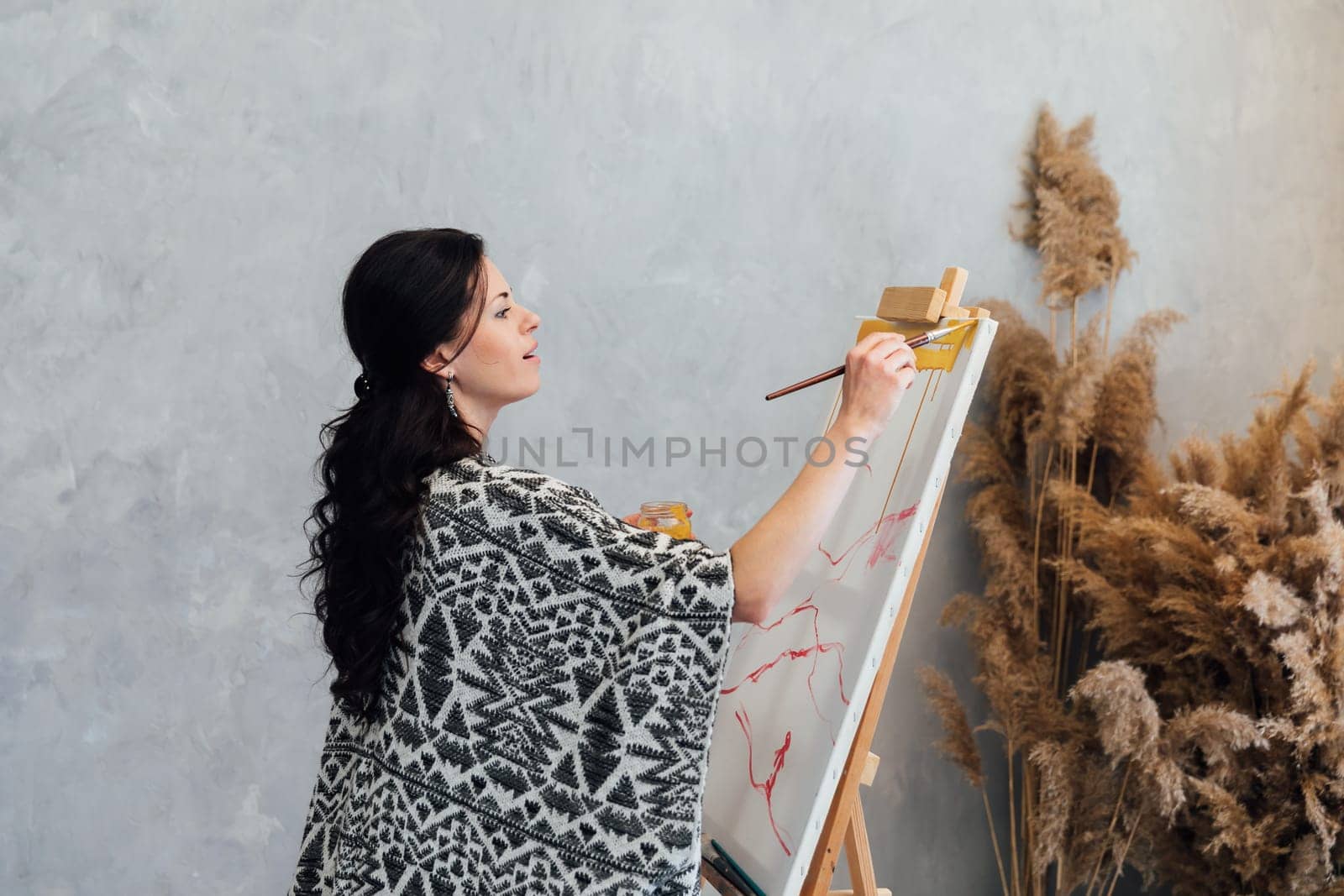 a woman artist paints a picture on an easel in an art studio