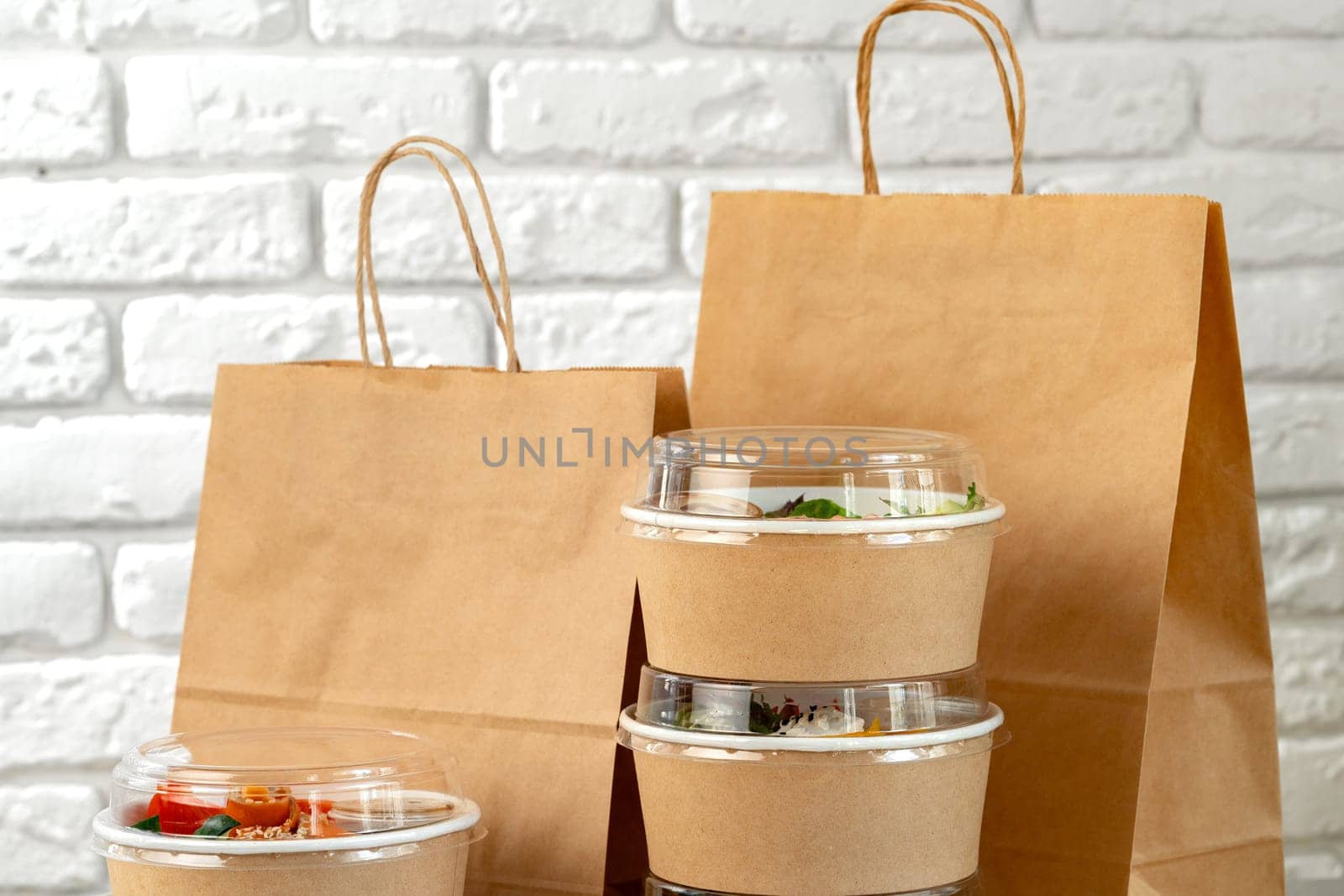 Take out food in boxes and craft bag against white brick background