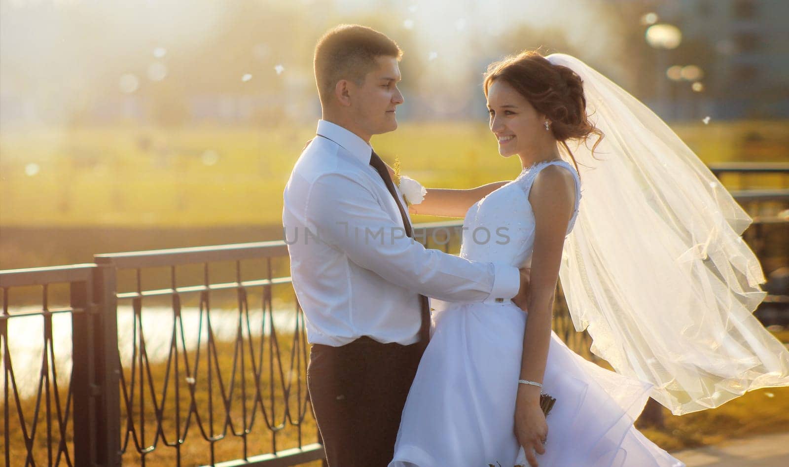 Happy groom hugging his bride holding a bouquet of white roses in her hands. High quality photo