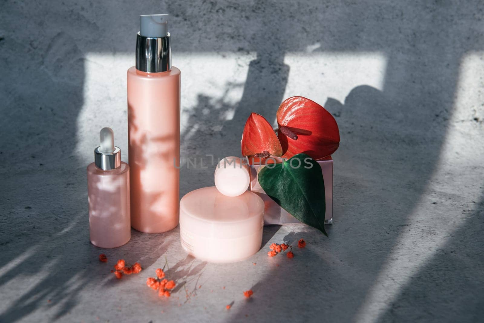 Cosmetic bootles with flowers o n gray background