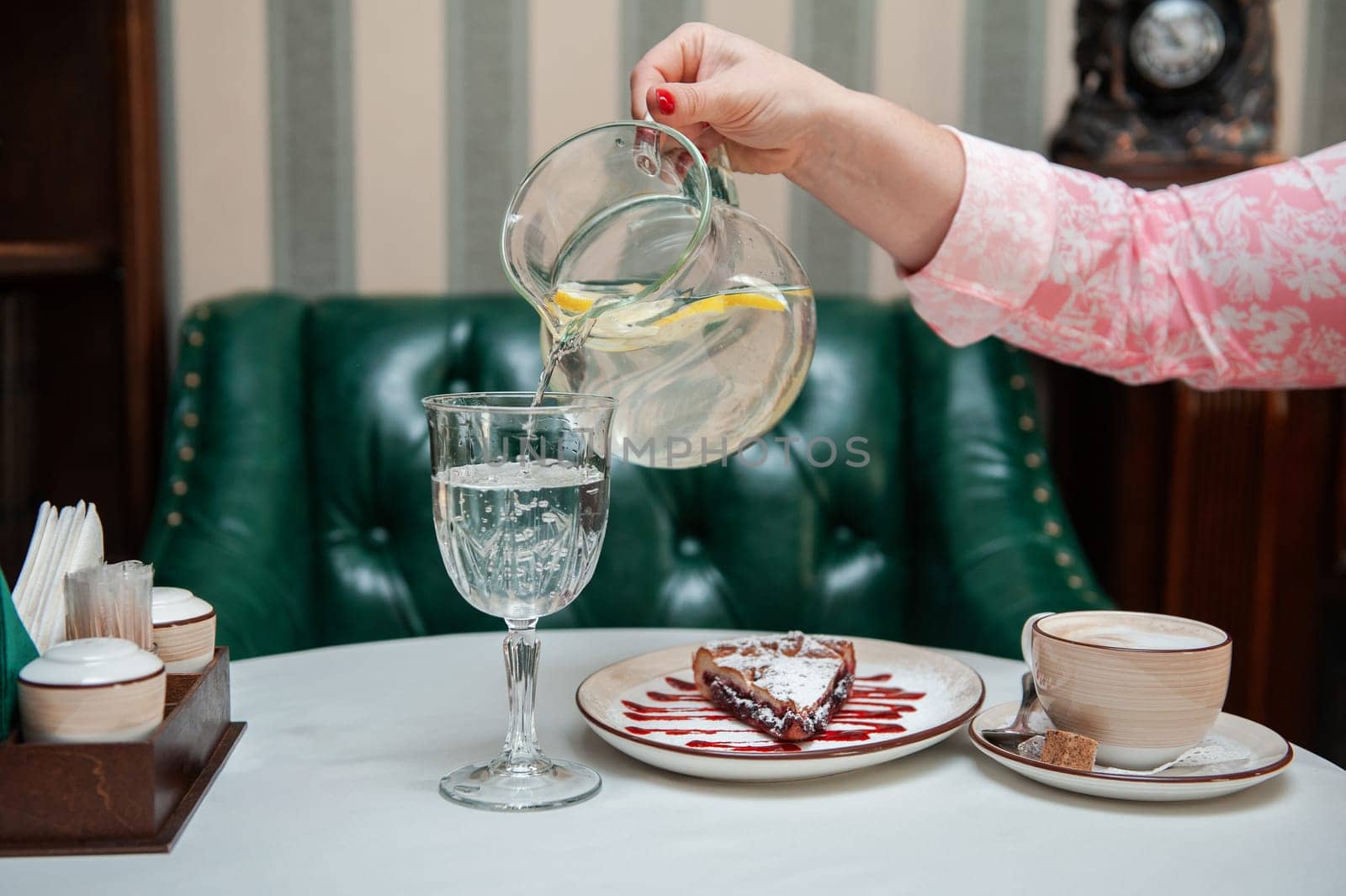 Closeup photo of female hands is reaching out to cake with cup of coffee in restaurant
