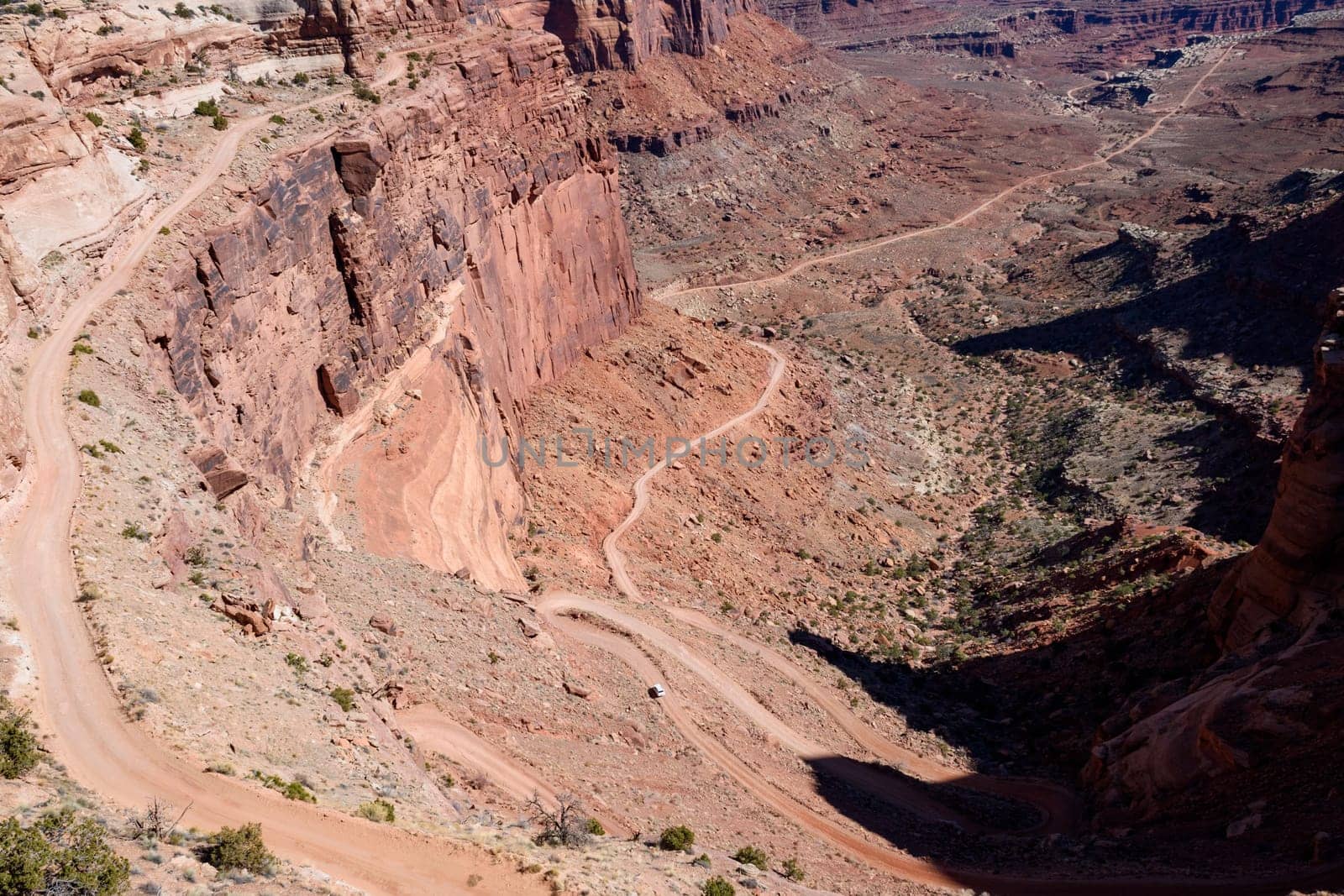 A breathtaking scenic view of the winding Shafer Trail in Canyonlands National Park, Utah. A car drives along the dirt road with dramatic cliffs in this iconic American Southwest landscape - USA