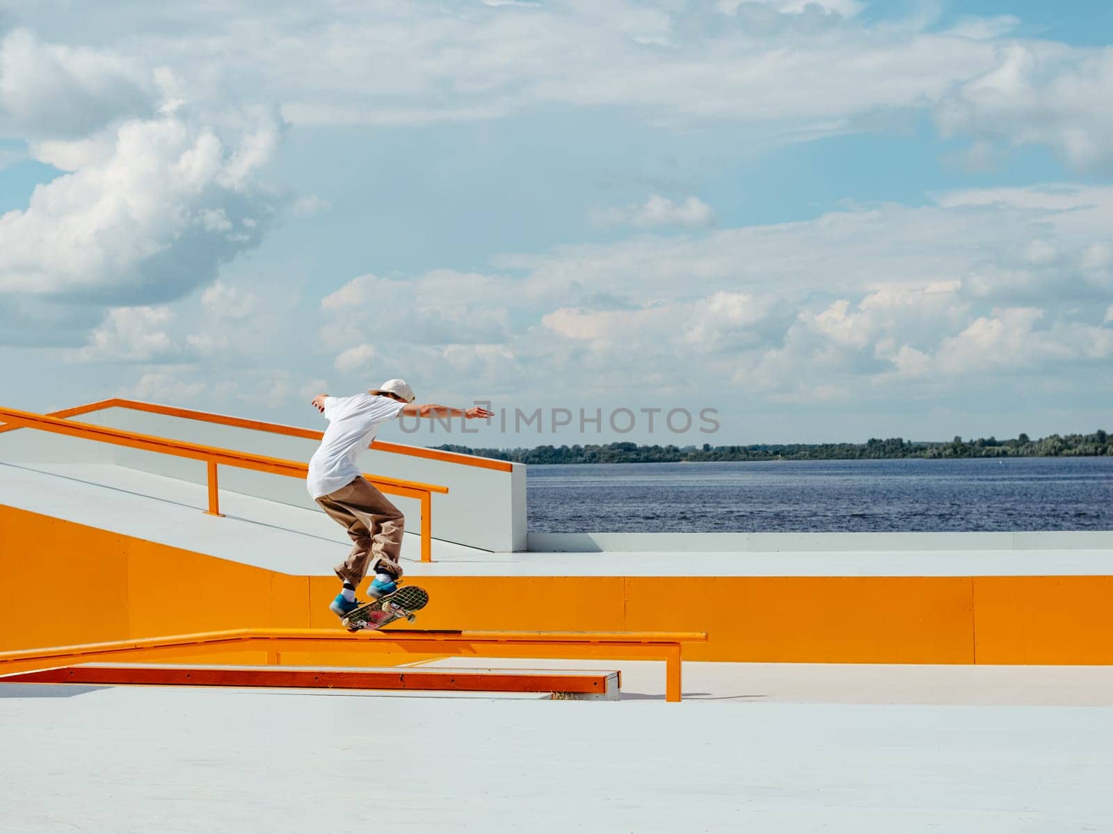 Caucasian Boy doing skateboard trick on rail in skatepark. Professional sportsman grinding on skateboard in outdoor park. Faceless unrecognizable young white skater doing Manual Grind trick on skate