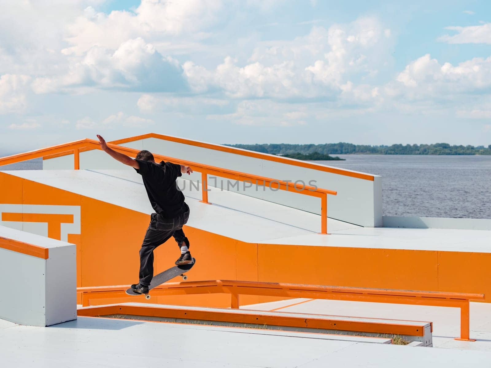 Latino Boy doing skateboard trick on rail in skatepark. Professional skater sportsman grinding on skateboard in outdoor park. Faceless unrecognizable Latin skater doing Grind trick. Skate background