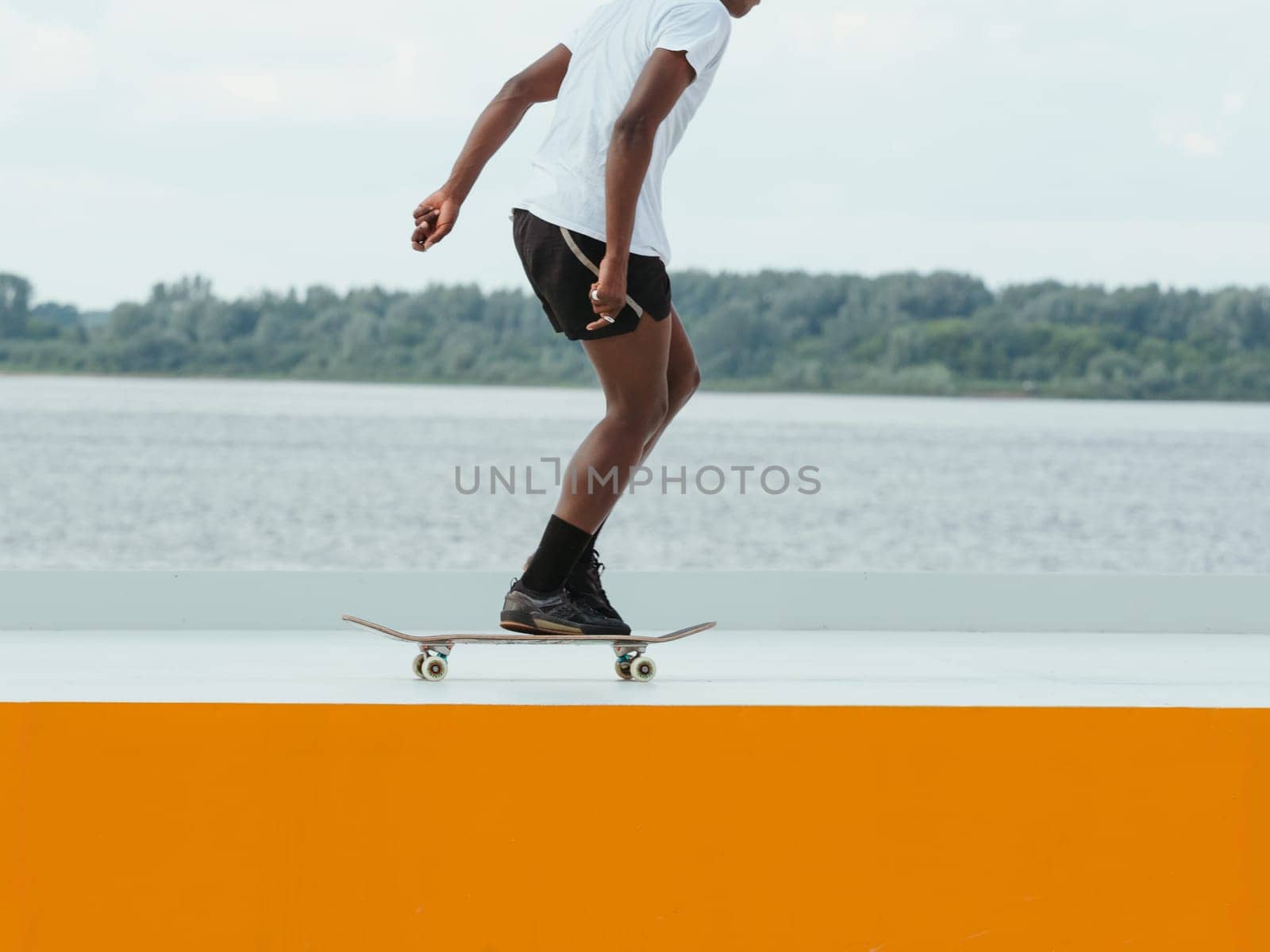African man riding a skateboard. Faceless unrecognizable professional Afro skater in shorts riding on skate. Modern sport, subculture and skateboarding concept. Skate as hobby healthy lifestyle