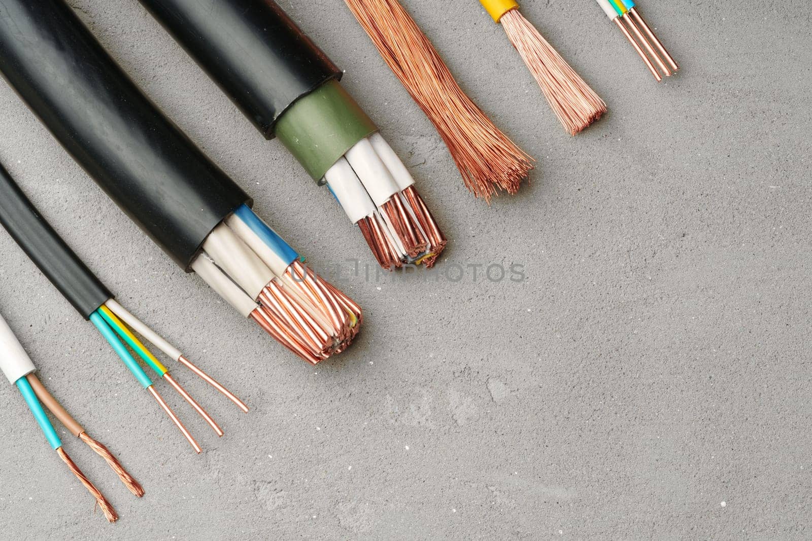 This image shows a variety of electrical tools and wires laid out on a gray surface.