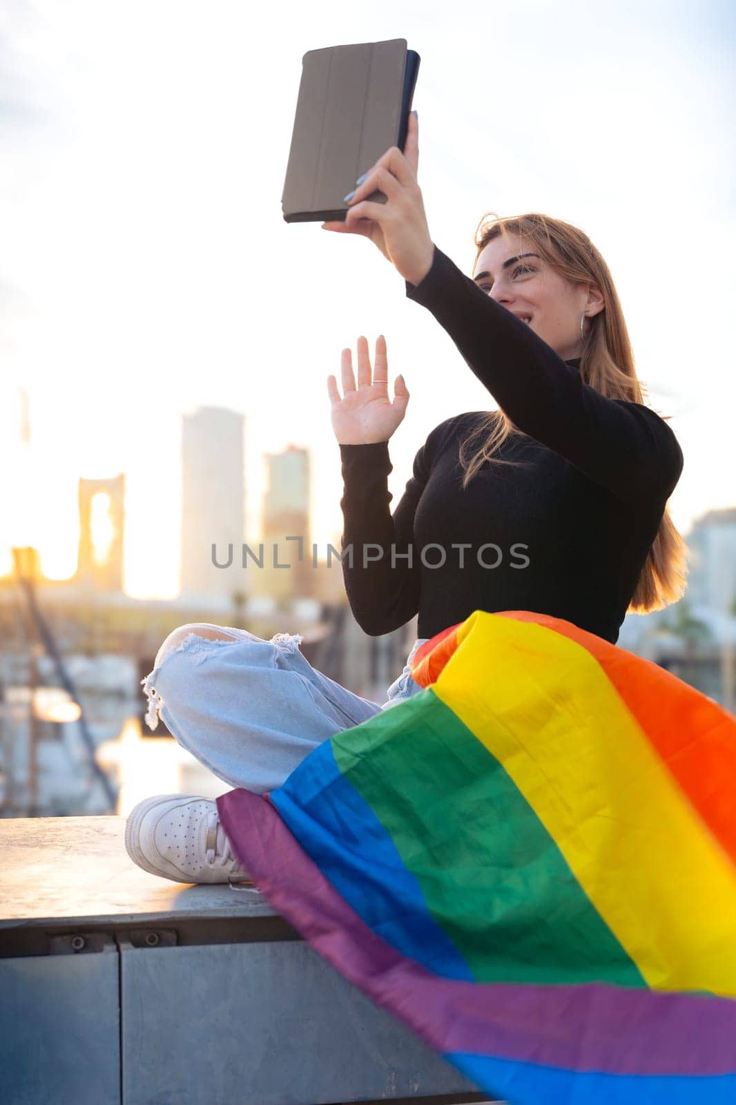 Young woman takes a selfie on the digital tablet with the lgtbi flag. Vertical by mariaphoto3