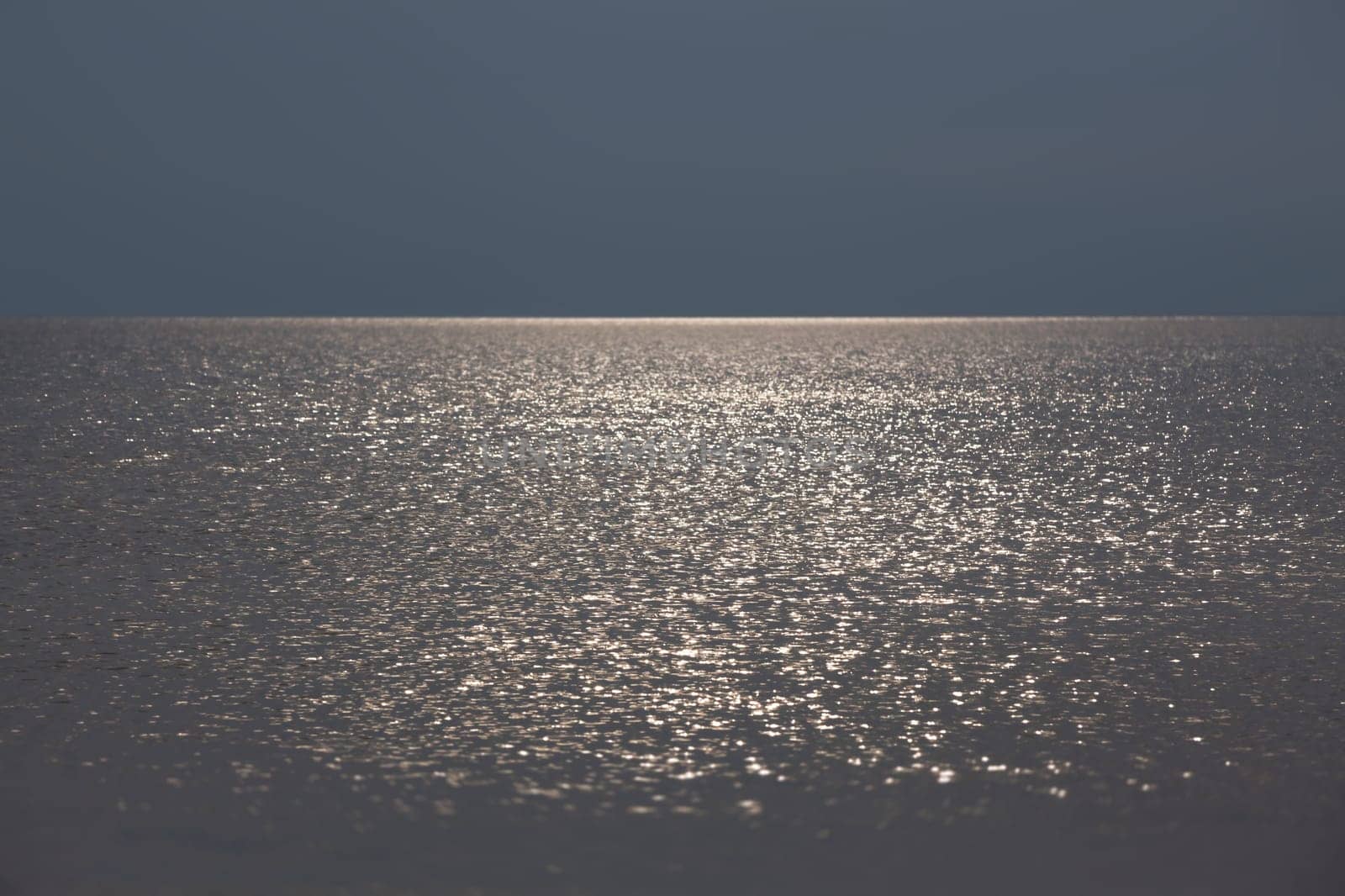 Sun glare on the sea surface in calm, breezy weather. Natural background and texture.