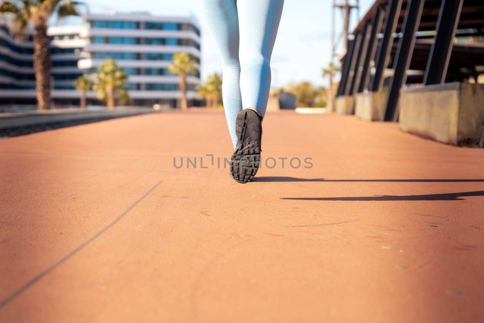 Feet of a sporty woman running through the streets of the city.