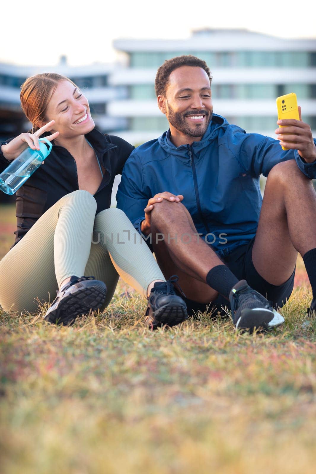 Young couple taking a selfie with their smartphone ready to exercise.Vertical by mariaphoto3