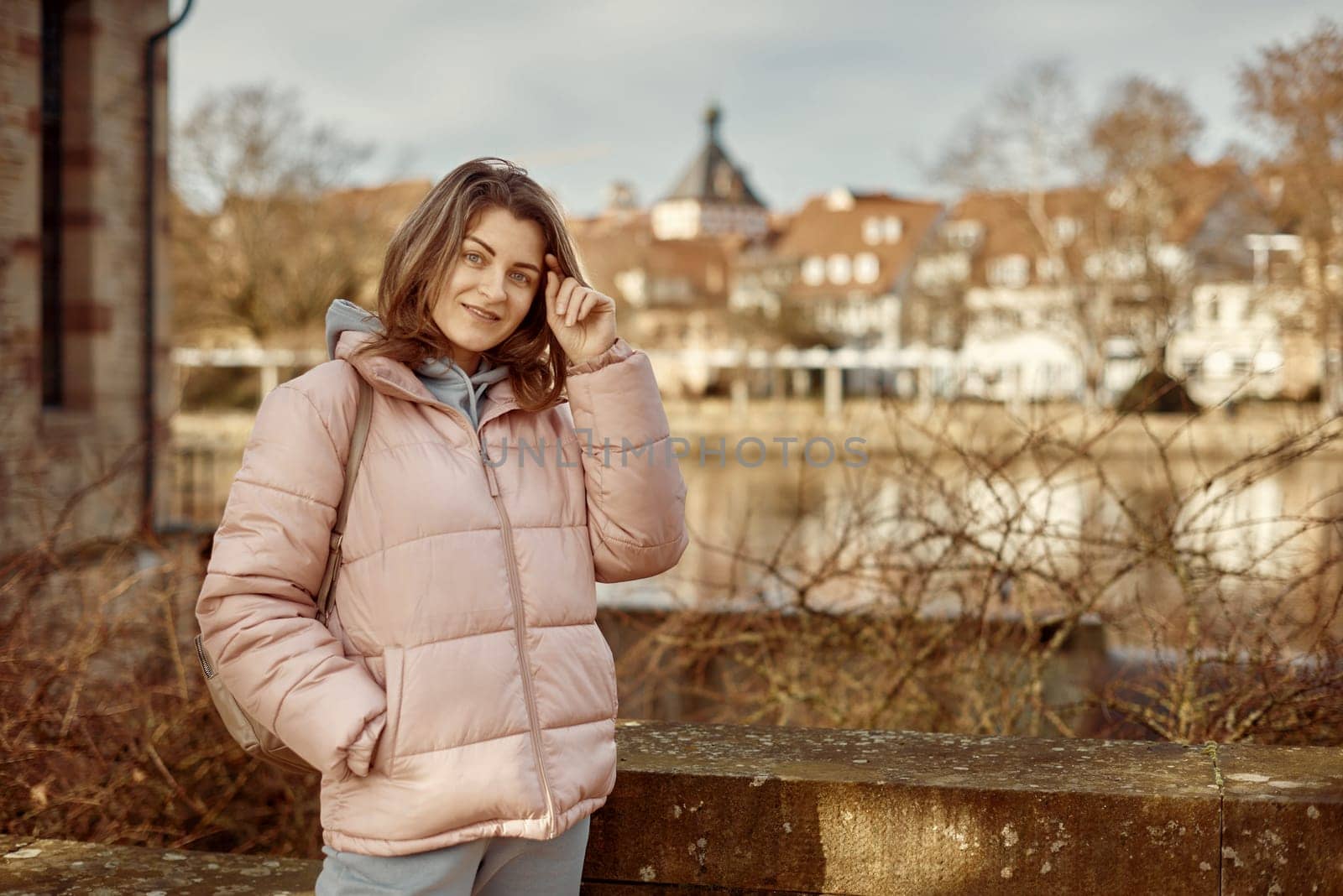 Young beautiful pretty tourist girl in warm hat and coat with backpack walking at cold autumn in Europe city enjoying her travel in Bietigheim-Bissingen, Deutschland. Outdoor portrait of young tourist woman enjoying sightseeing by Andrii_Ko