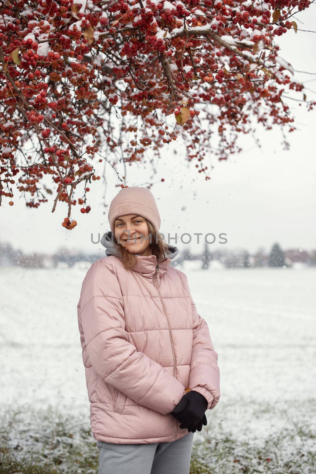 Winter Elegance: Portrait of a Beautiful Girl in a Snowy European Village. Winter lifestyle portrait of cheerful pretty girl. Smiling and having fun in the snow park. Snowflakes falling down. Christmas Radiance: Capturing Winter Elegance in the Snowy Ambiance of a European Village by Andrii_Ko