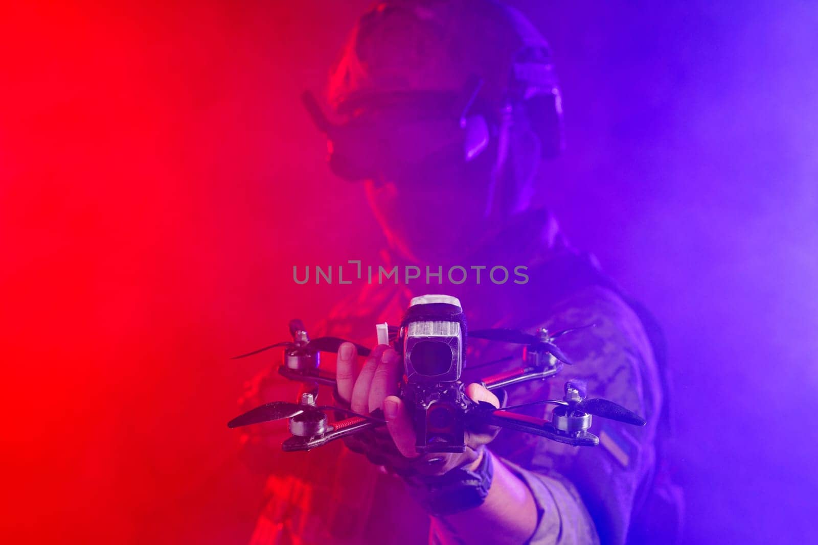 Soldier in gear holds drone against a red and blue smoky background, conveying intensity and military action