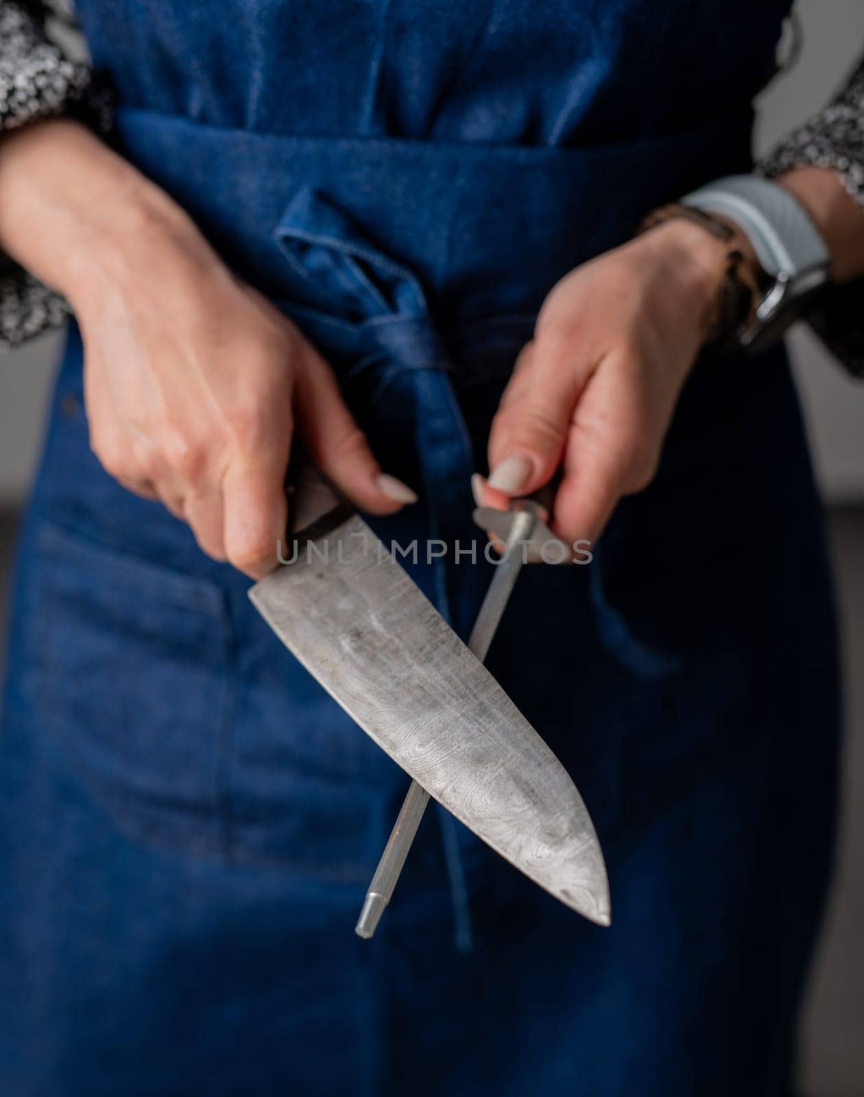 Big Kitchen Knife And Sharpener In Female Hands Are In Close-Up View
