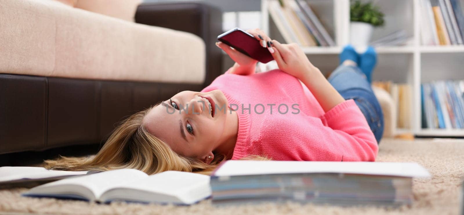 young beautiful woman have a rest lie on the floor hold smartphone in arms nice holiday concept