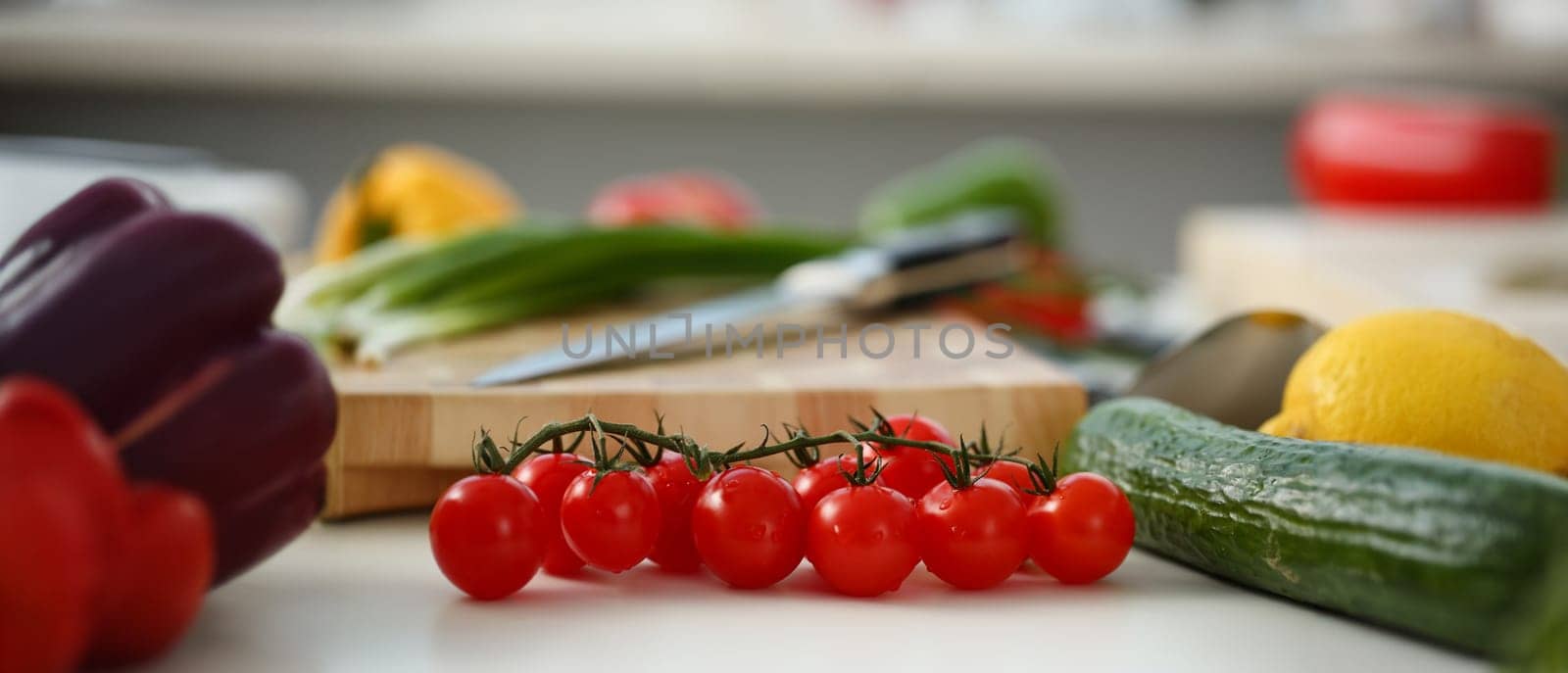 Cherry tomatoes lie on a cutting board in kitchen against backdrop of greenery healthy eating concept