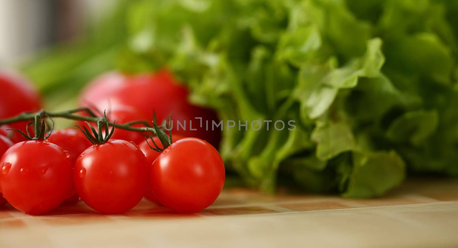 Cherry tomatoes lie on a cutting board in kitchen against backdrop of greenery healthy eating concept
