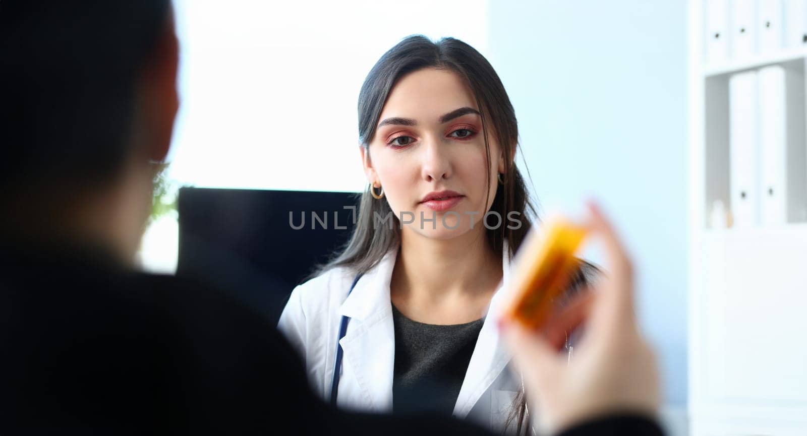 Female medicine doctor hand hold jar of pills and write prescription to patient at worktable. Panacea and life save prescribing treatment legal drug store concept.
