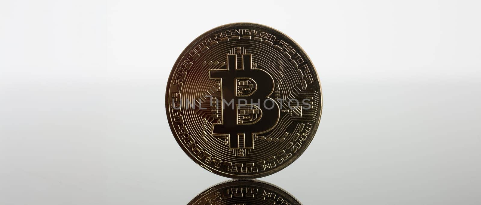 Coin of crypto currency bitcoin on a gray-blue background with reflection subject gold exchange pyramid on money in connection with the growth or fall exchange rate closeup.