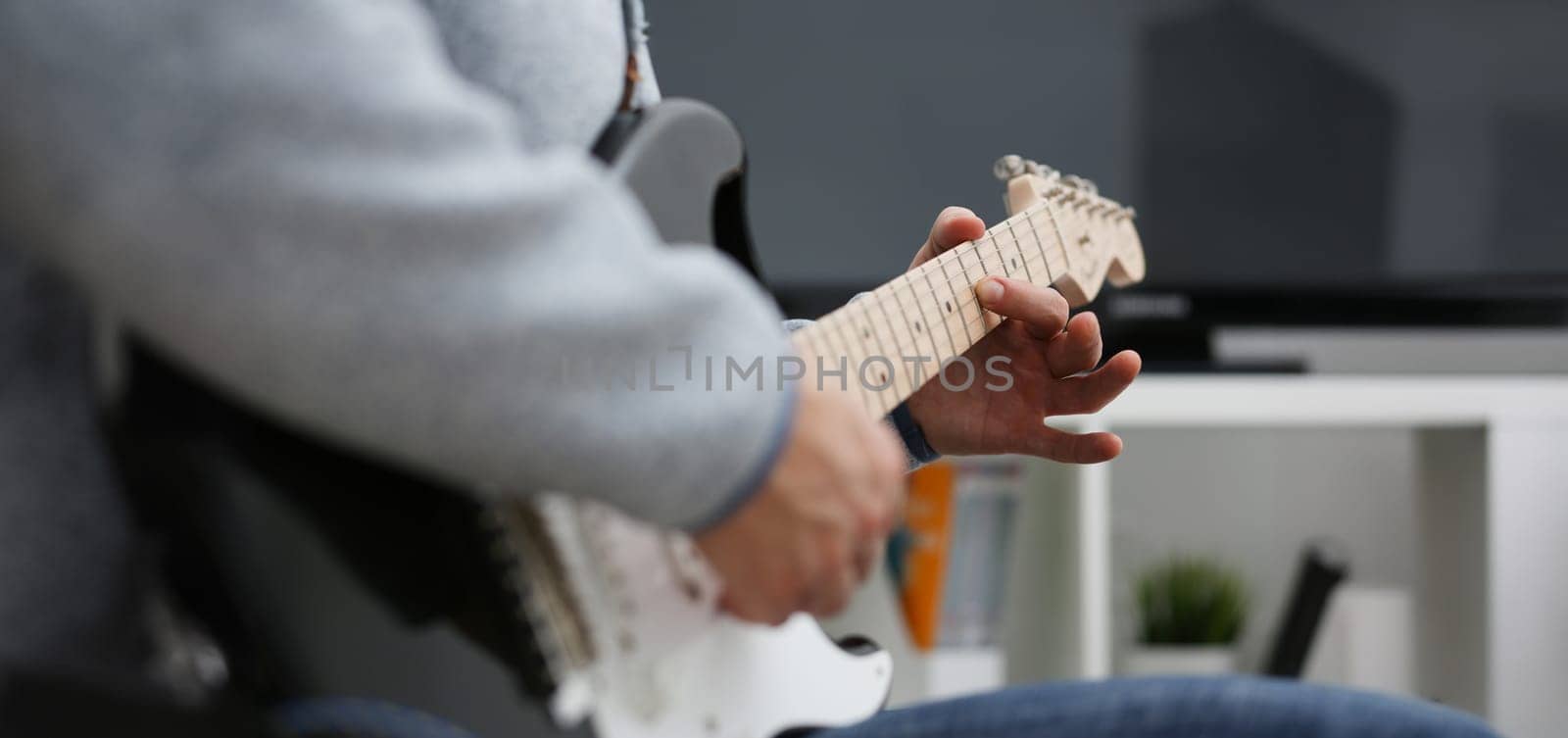 Male hands at home play and tune the electric guitar is engaged in music realizes listening enjoying music notation large concept closeup