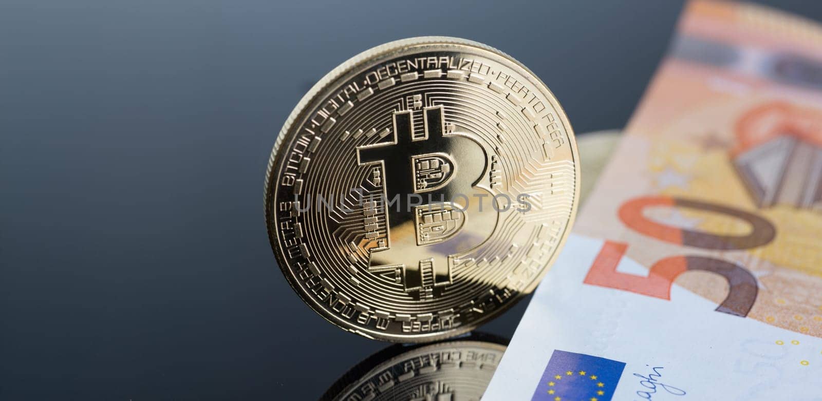 The coin of crypto currency bitcoin against background euro banknote subject gold exchange pyramid for money in connection with the growth or fall exchange rate closeup.