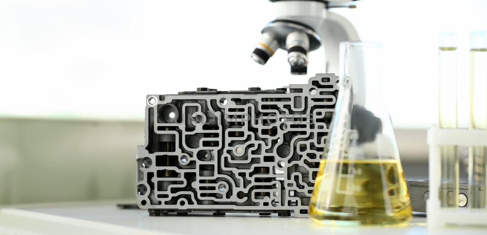 Test tube chemistry flask against background of hydroblock acp with yellow liquid purified oil from recycling and lubricating materials sale closeup