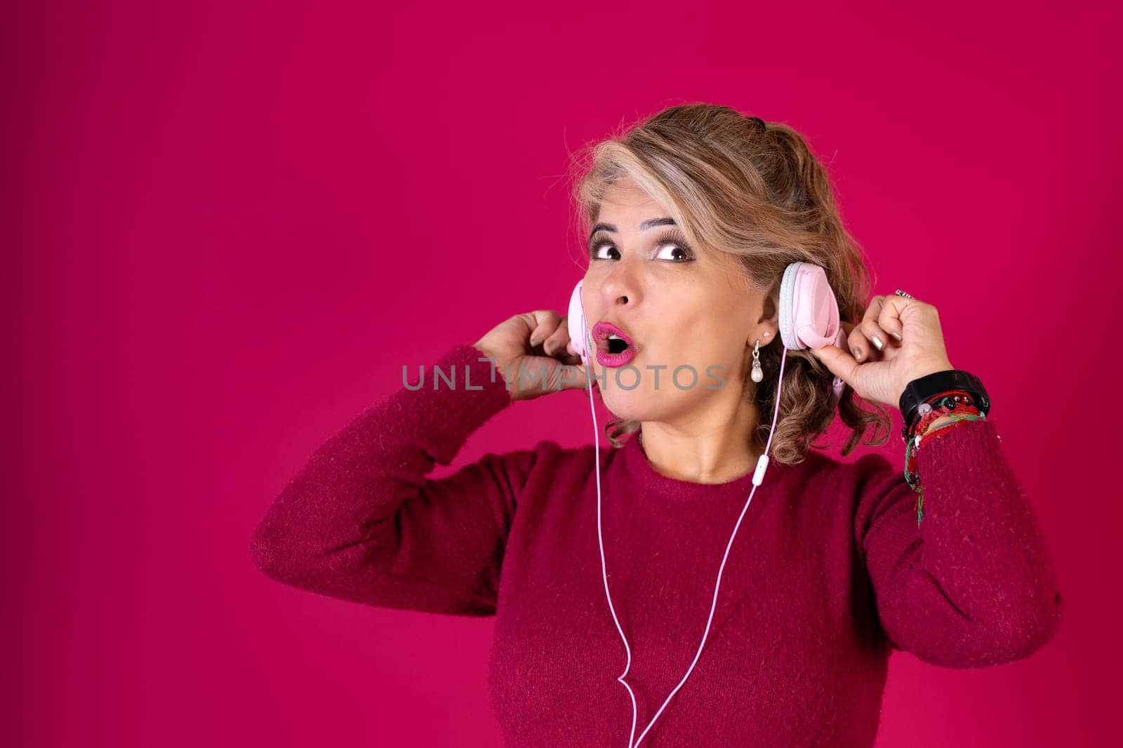 A woman wearing headphones and a red shirt. She is looking at the camera with her mouth open