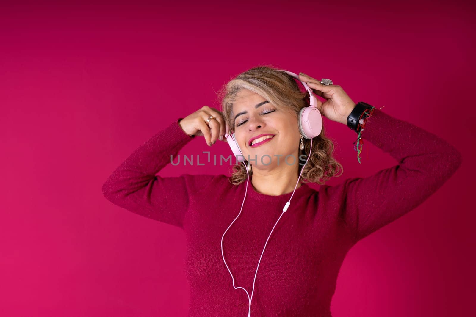 A woman is wearing headphones and smiling while listening to music. Concept of relaxation and enjoyment as the woman immerses herself in the music