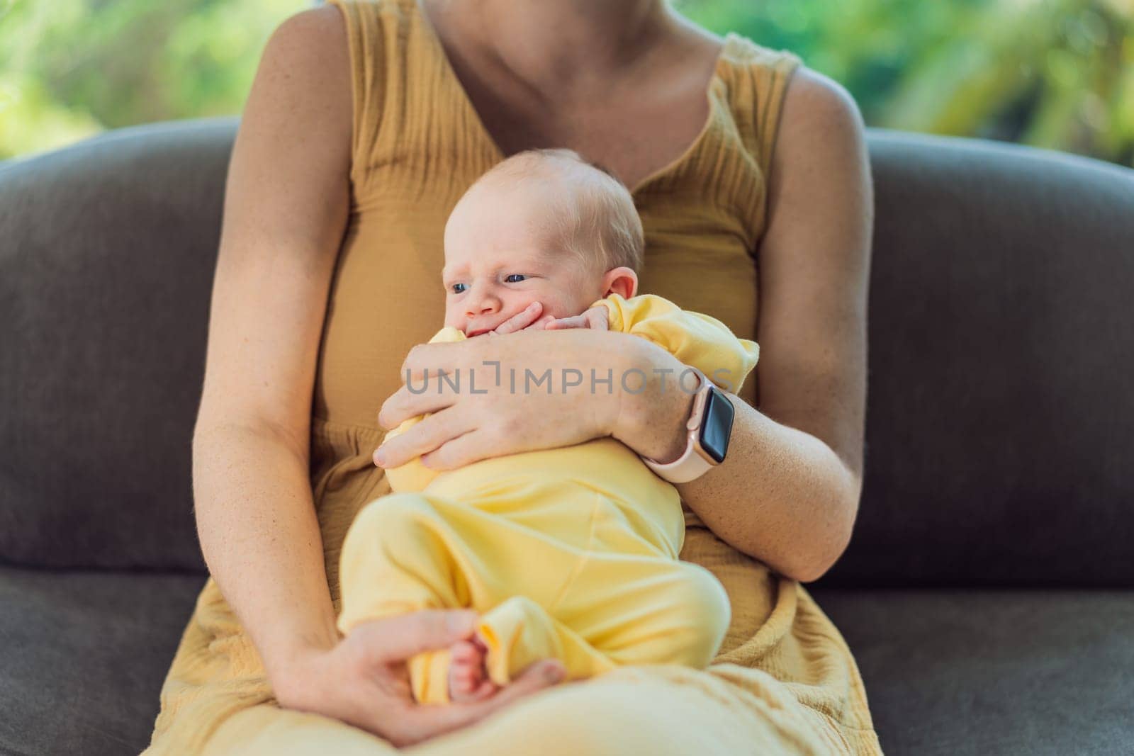 Mom with newborn baby relaxing on the sofa at home. This tender moment highlights the bond between mother and child in a comfortable and loving family environment.