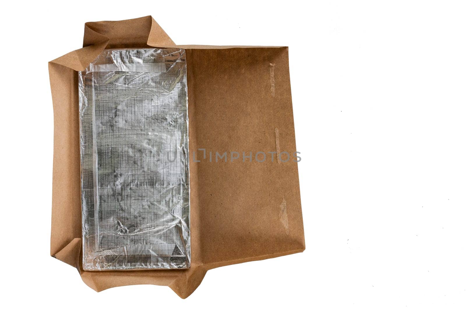 Chocolate in foil with opened paper packaging on a white isolated background, top view.