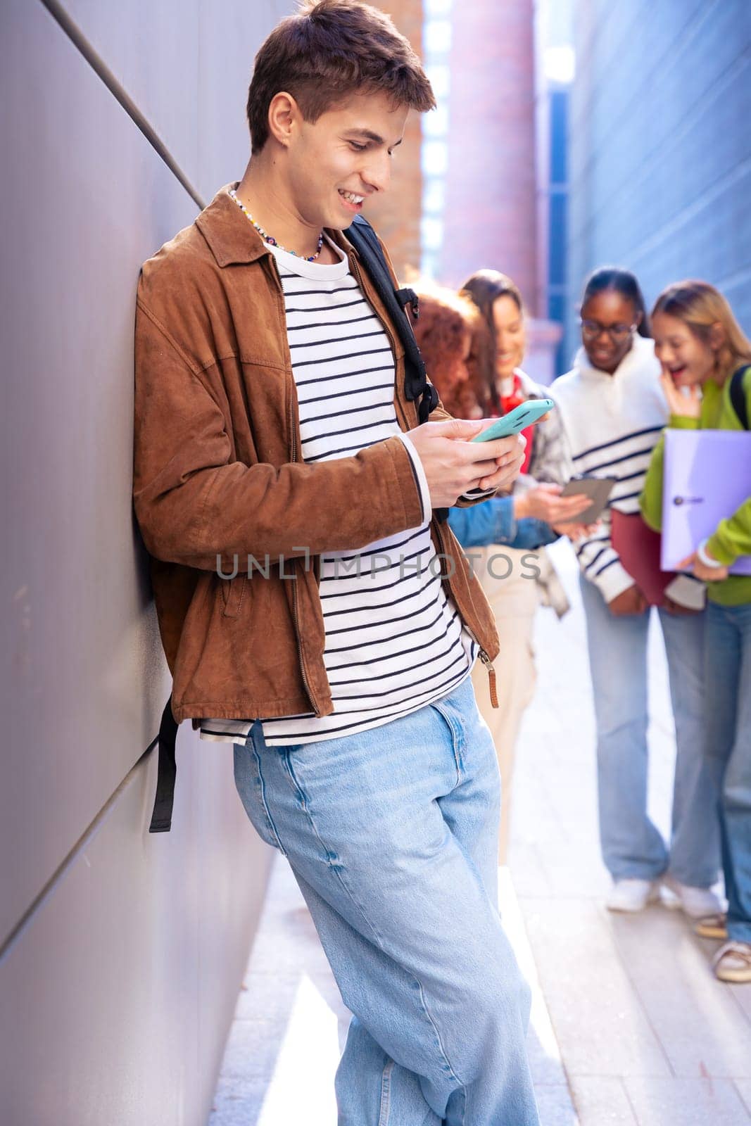 Young smiling student with notebook in hand uses social networks with smartphone applications and wireless technology outdoors.