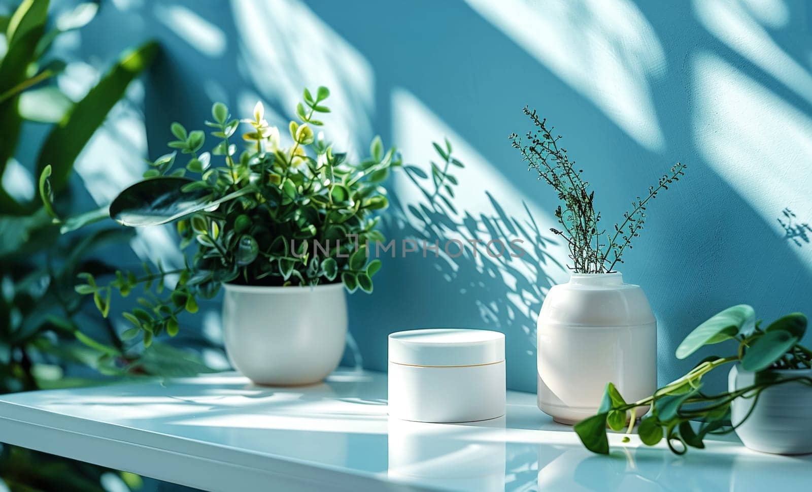 Cosmetic Composition. Beautiful blue pastel color cosmetic skincare makeup containers standing on white table. On the wall reflects the sunlight and shadows. Women make up concept. Copy space.