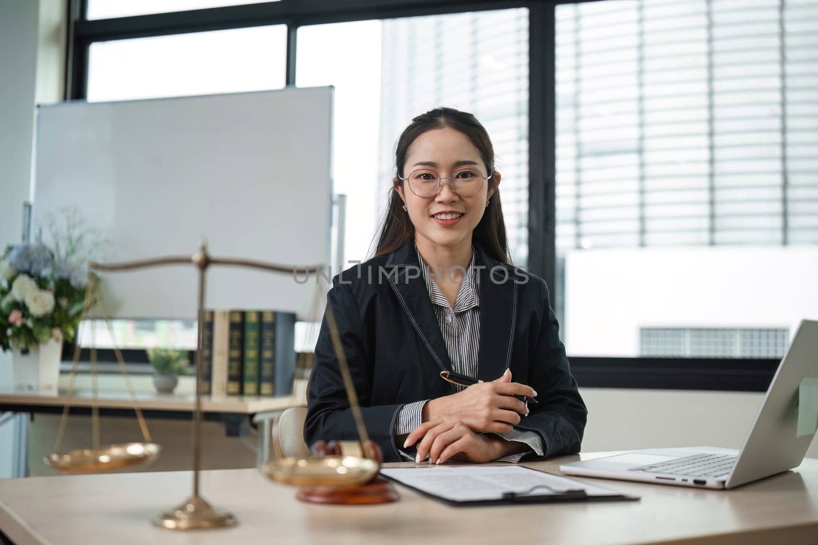 A professional female lawyer examines contract documents related to a lawsuit in a modern office environment.