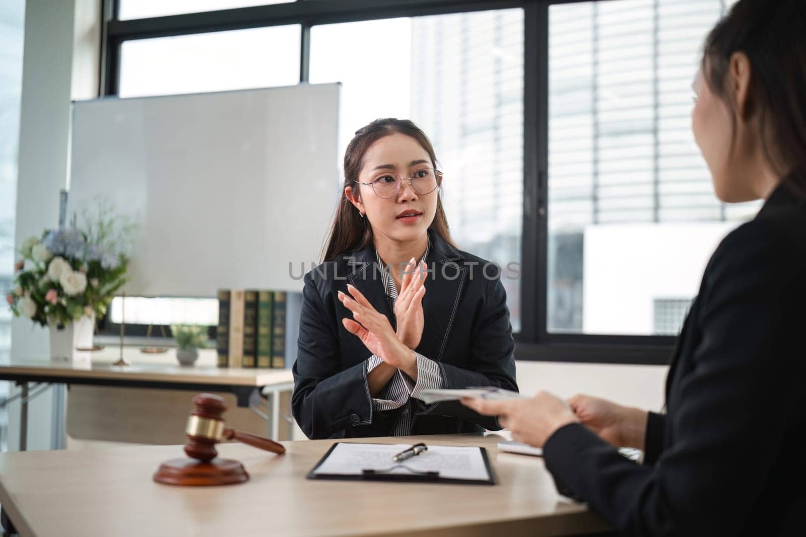 A professional female lawyer confidently denies corruption allegations during a client consultation in a modern office environment.