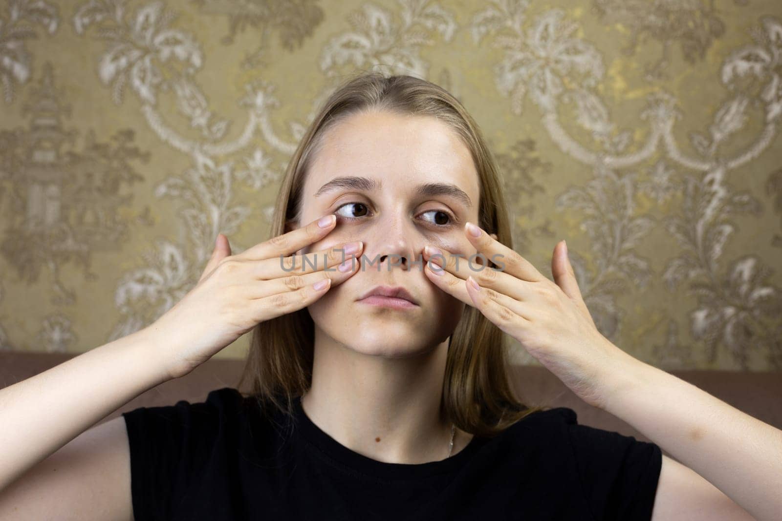 Young girl massages her face with hands for skin care, warming up the facial tissues of girl for beauty procedure