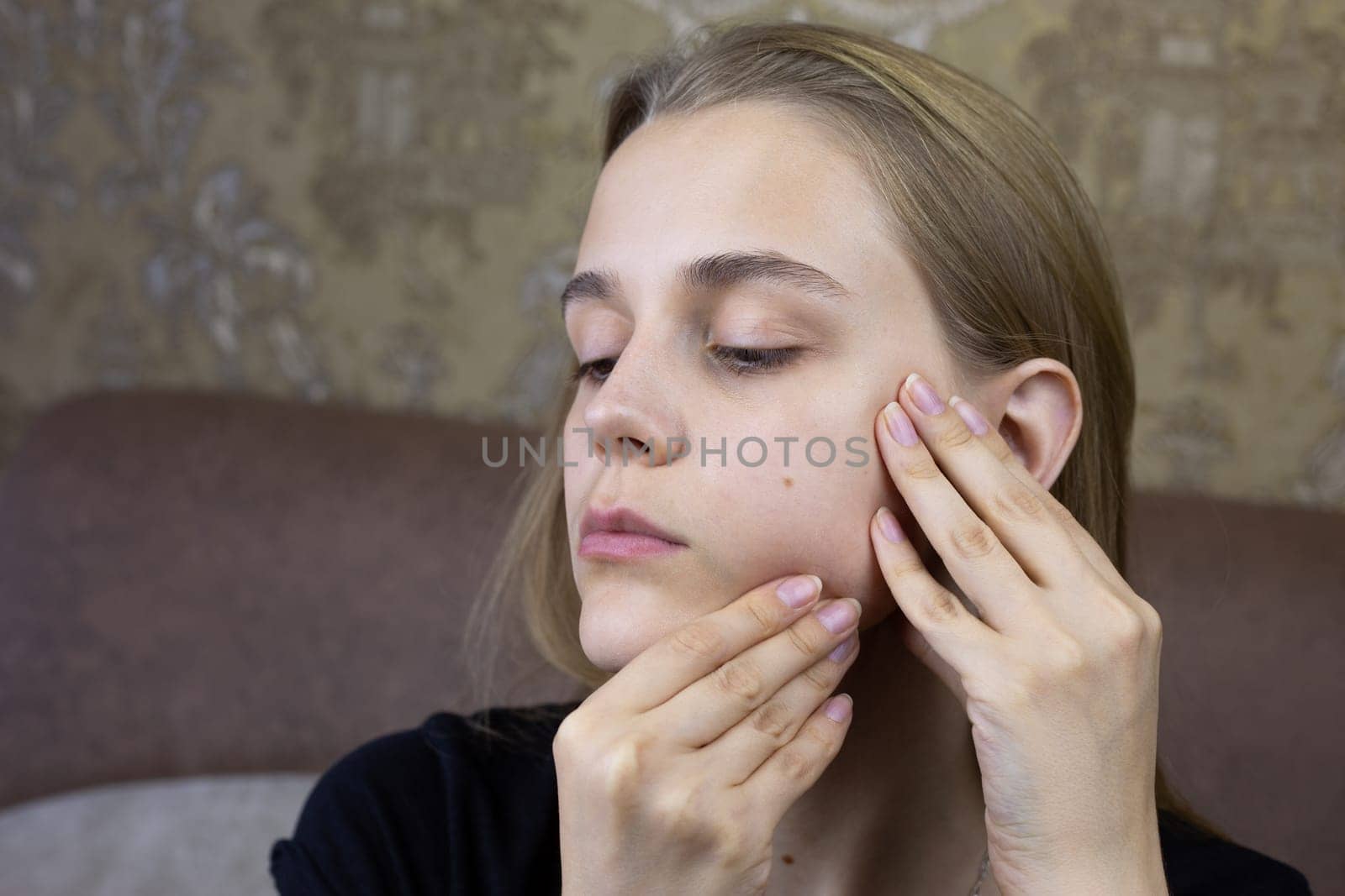 European young girl makes facial massage with her hands to herself, special skin care product for the girl face