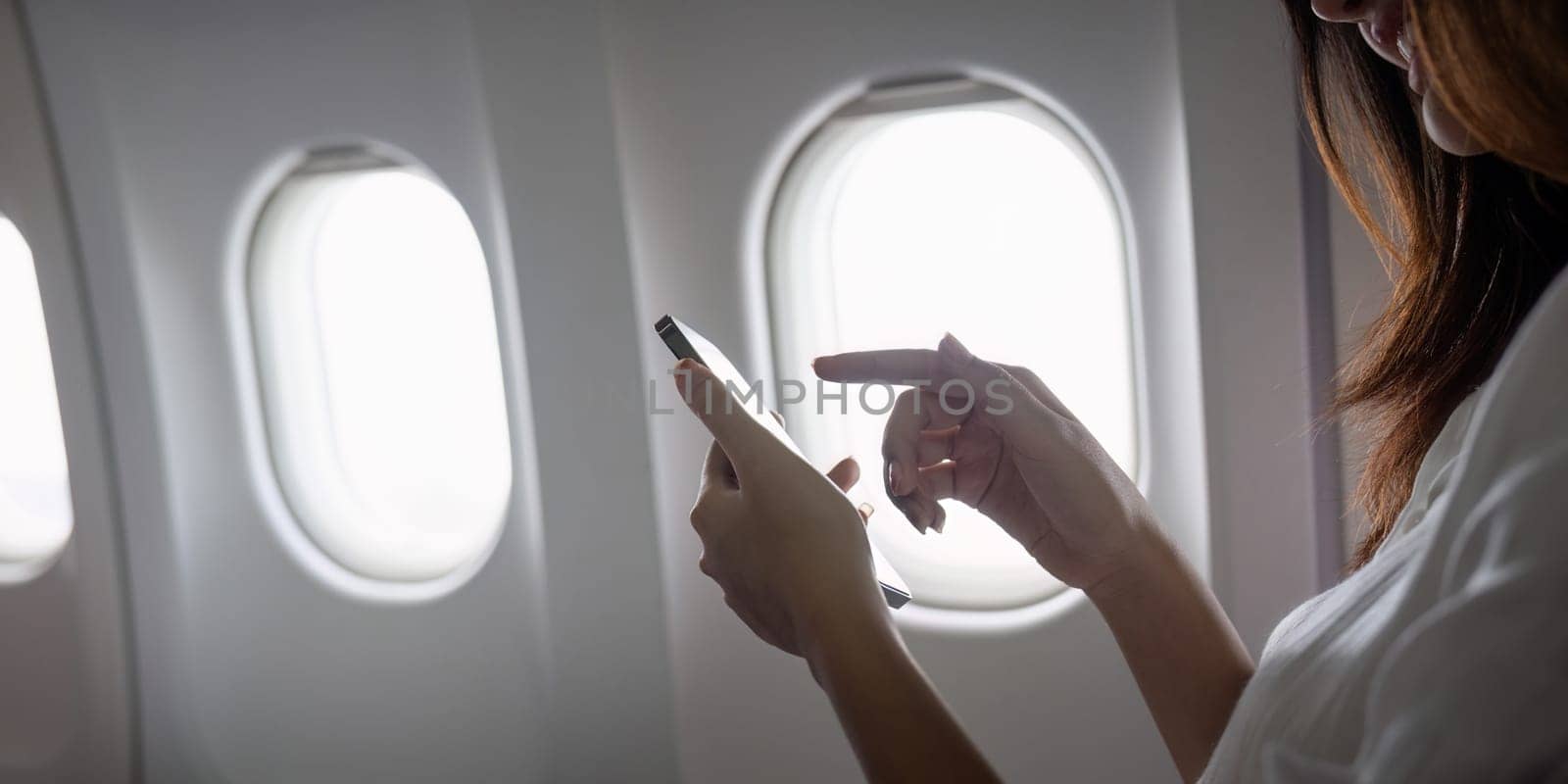 Modern Technology in Air Travel, Passenger Using Smartphone on Airplane for Connectivity and Entertainment by nateemee